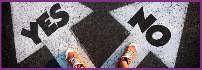 A person's feet wearing orange sneakers standing on pavement with large "YES" and "NO" text painted on the ground